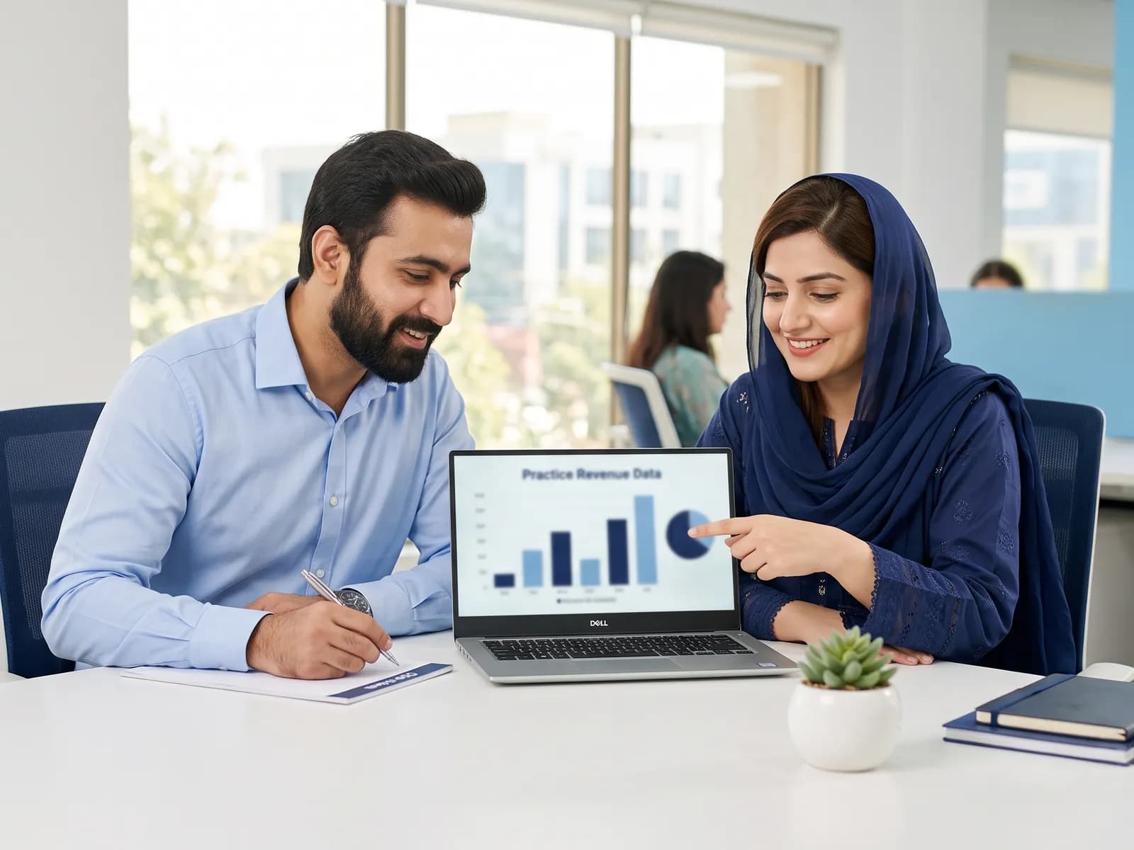 Billing specialist and practice manager reviewing a revenue chart together on a laptop